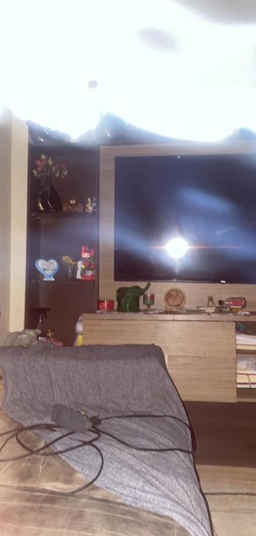 a bedroom with a bed and a large tv at Condomínio azul in Paraty
