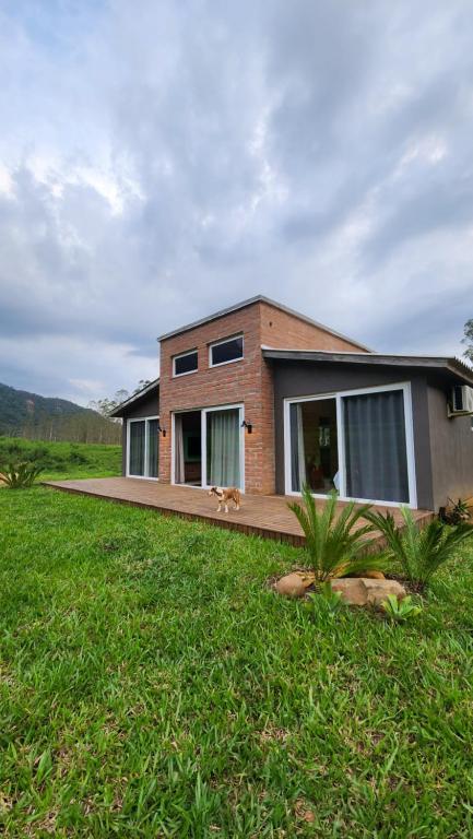 a house with a dog sitting outside of it at CASA GRÊS - Pousada Vale das Escarpas in Timbe do Sul