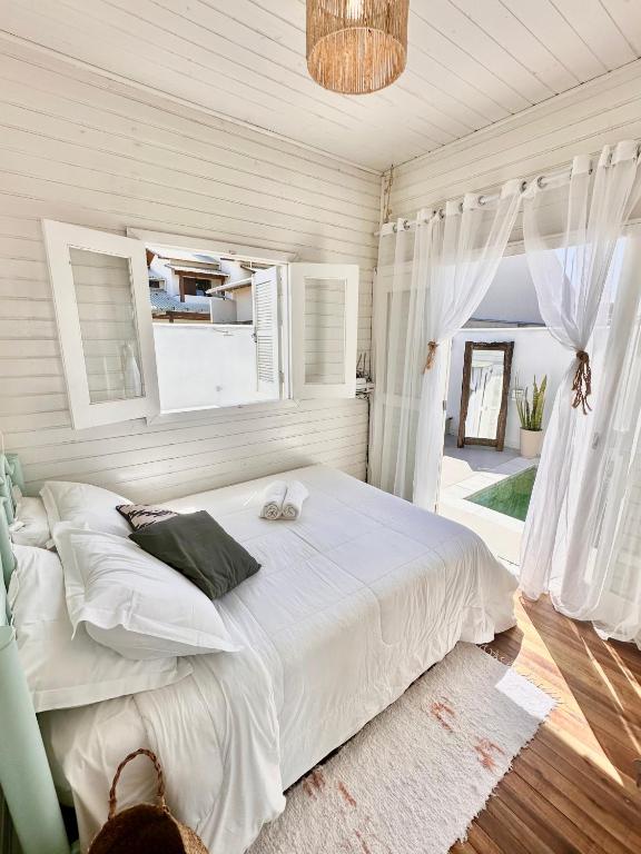 a bedroom with a large white bed with a window at A Casinha de Madeira in Balneário Gaivotas