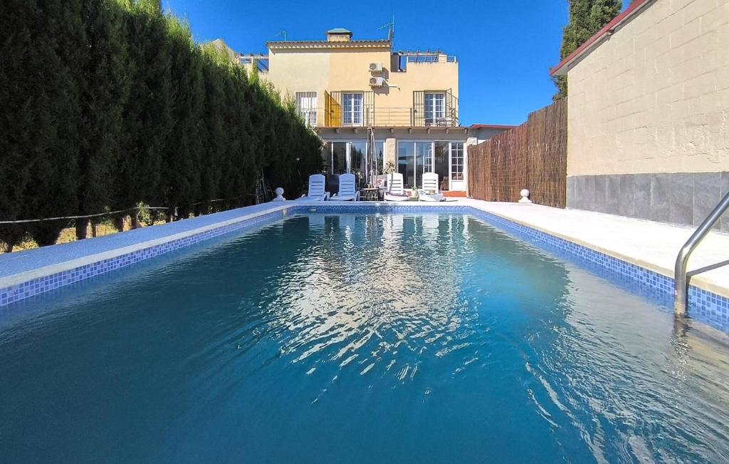 a swimming pool with blue water in front of a house at Cozy Home In Guillena in Guillena