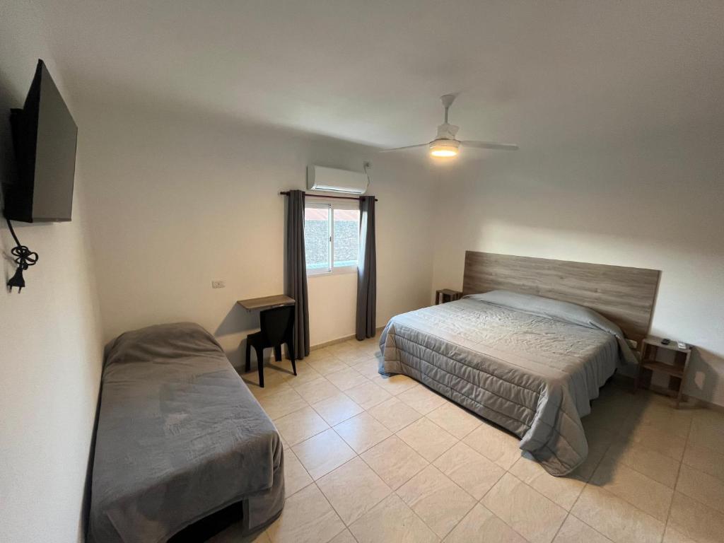 a bedroom with a bed and a desk and a window at Costumbres Argentinas Triples En suite in Avellaneda