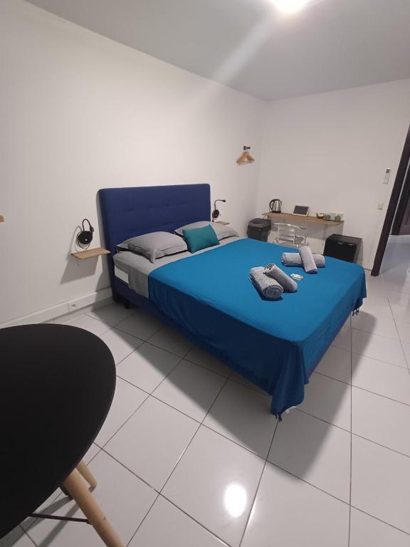 a bedroom with a blue bed in a white room at B787 - City center room Papeete in Papeete