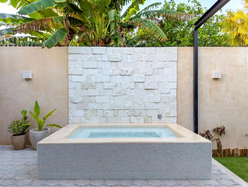 a hot tub in a backyard with a stone wall at Suite Premium con piscina privada en Valladolid - Penca Leonor 12 in Valladolid