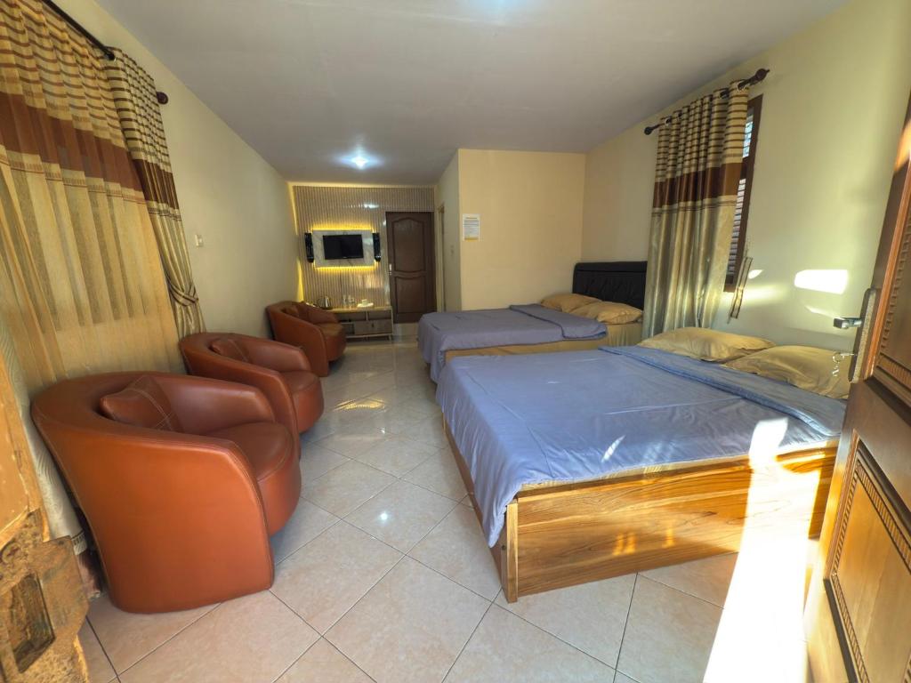 a hotel room with two beds and two chairs at Homestay Lereng Bromo in Bromo
