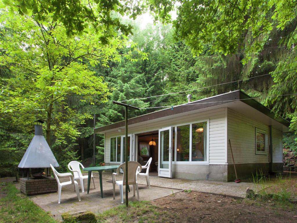 a small house with a table and chairs in front of it at Forest Chalet in Lanklaar in Lanklaar