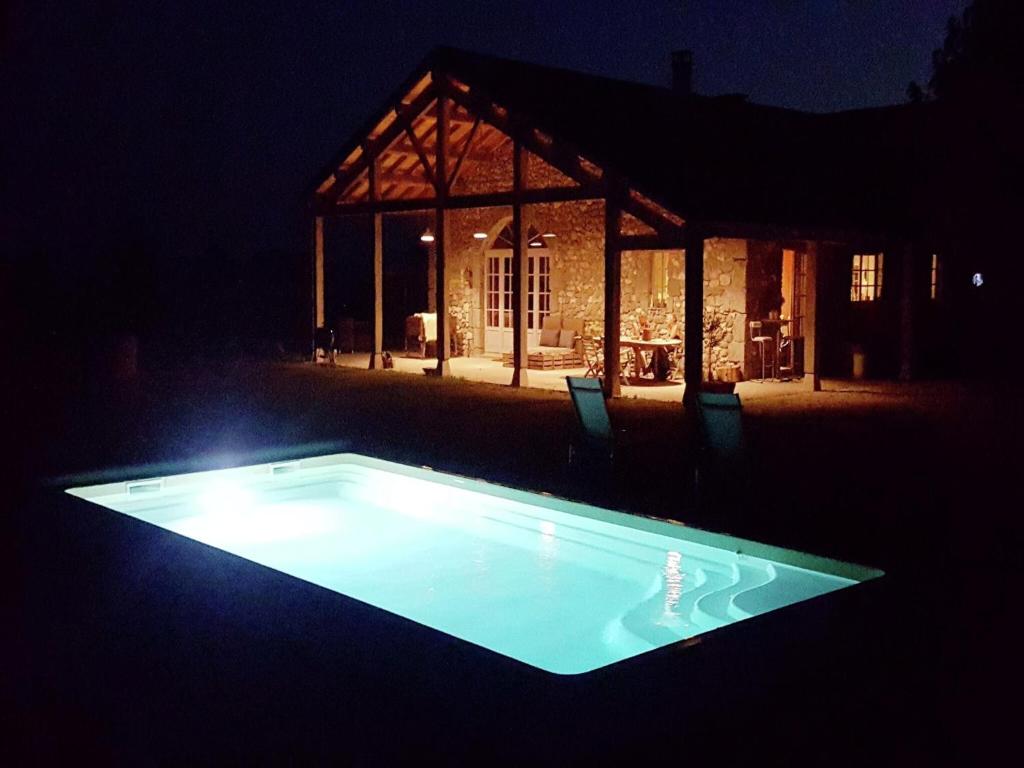 a swimming pool in front of a house at night at Family Château Retreat in Fargues-sur-Ourbise