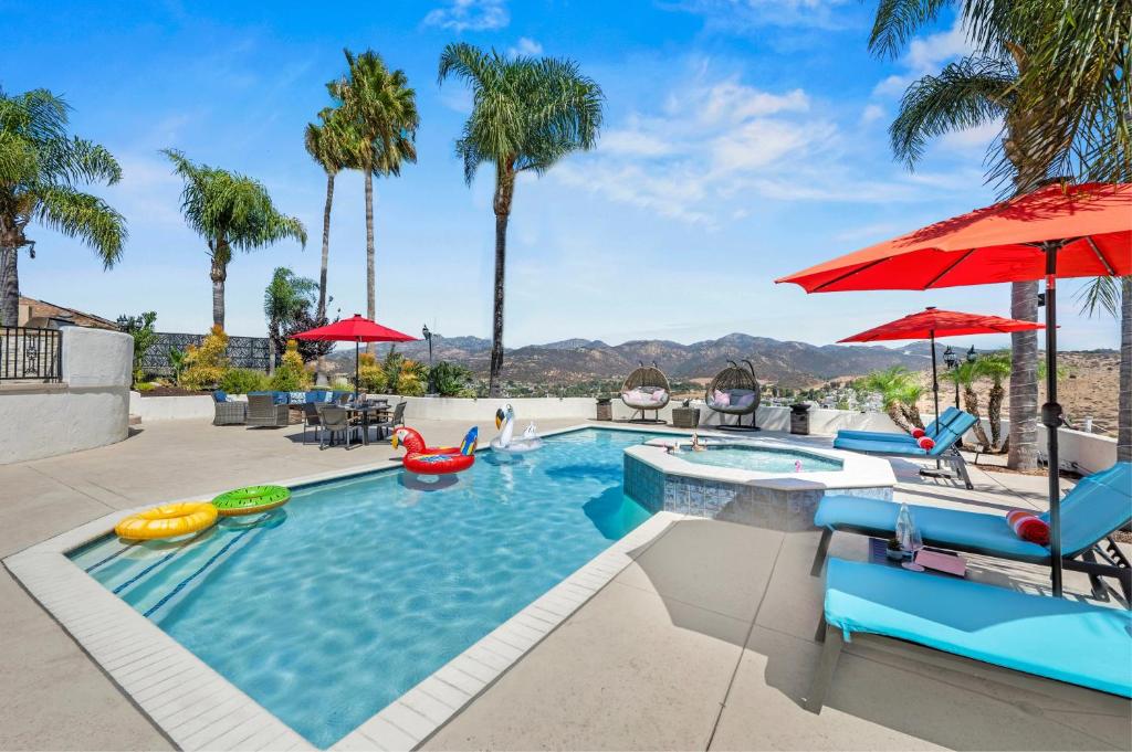 a swimming pool with chairs and umbrellas at Panorama Peak Luxury Retreat in Poway