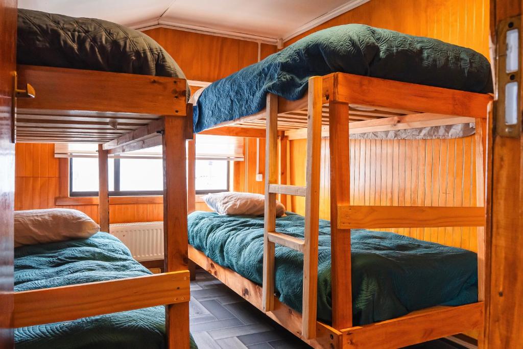 two bunk beds in a room with wooden walls at Isla yu backpacker in Puerto Natales