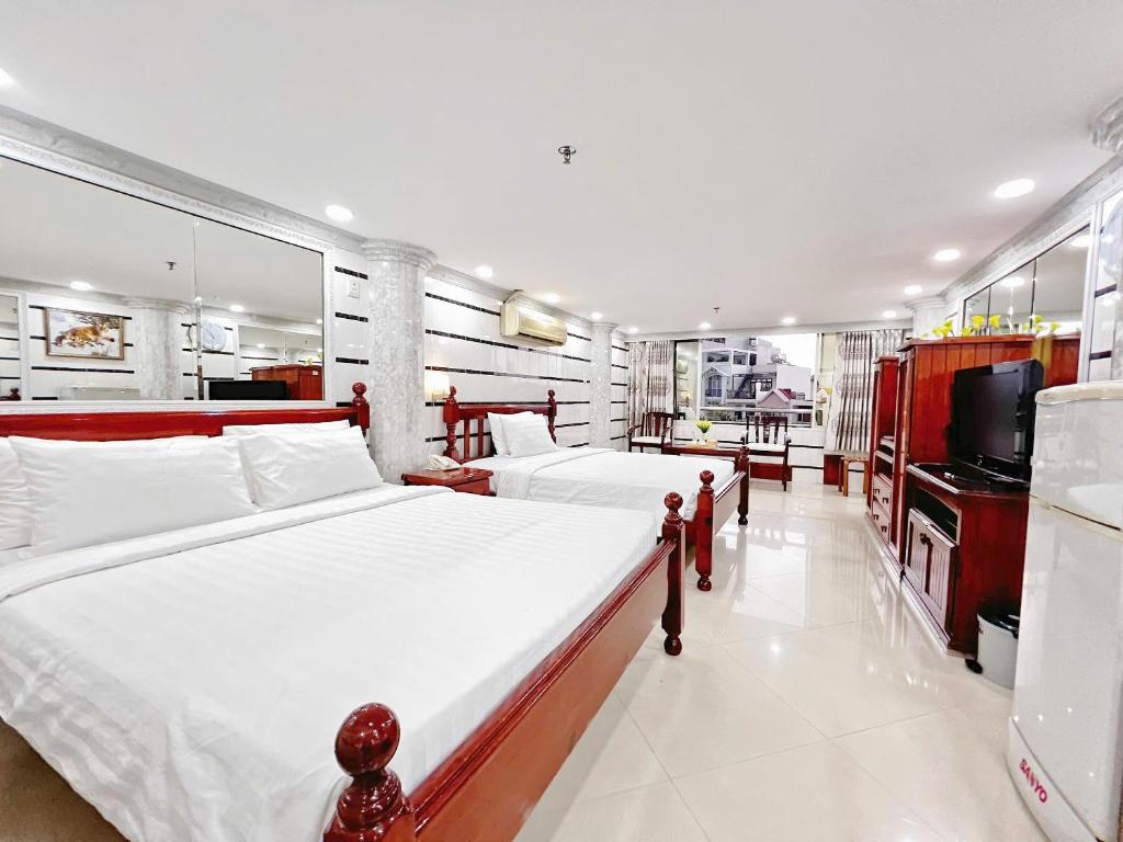 a bedroom with two beds and a flat screen tv at KT SG Hotel - Center in Ho Chi Minh City