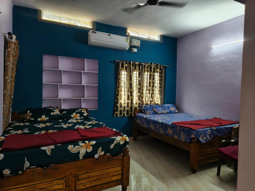 a bedroom with two beds and a blue wall at krishna yadav homestay in Hospet