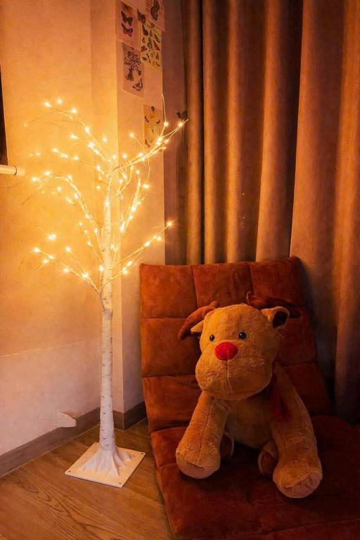 a teddy bear sitting next to a small tree with lights at AN BÌNH Home in Hai Phong