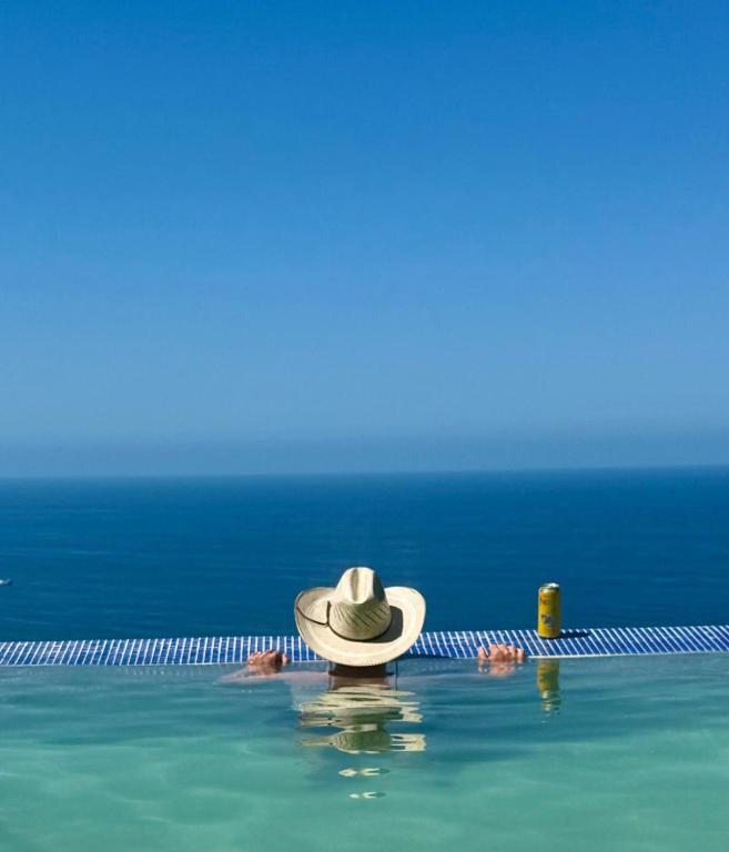 a person in a hat in the water near a swimming pool at The Sanctuary above Lo De Marcos in Lo de Marcos