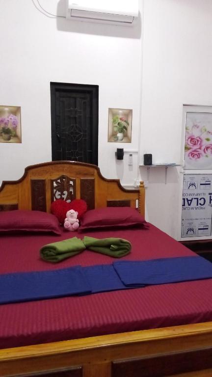 a bedroom with a large wooden bed with red sheets at Zeenath Villa - Arugambay in Arugam Bay