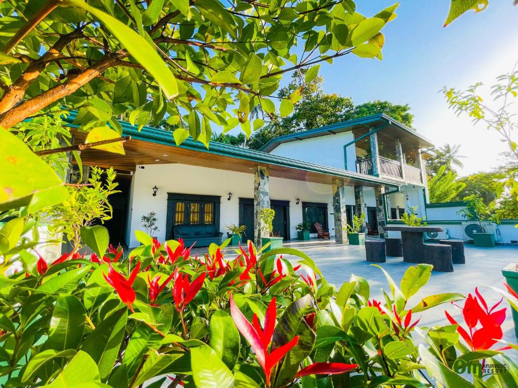 a building with red flowers in front of it at Om Hotel in Unawatuna