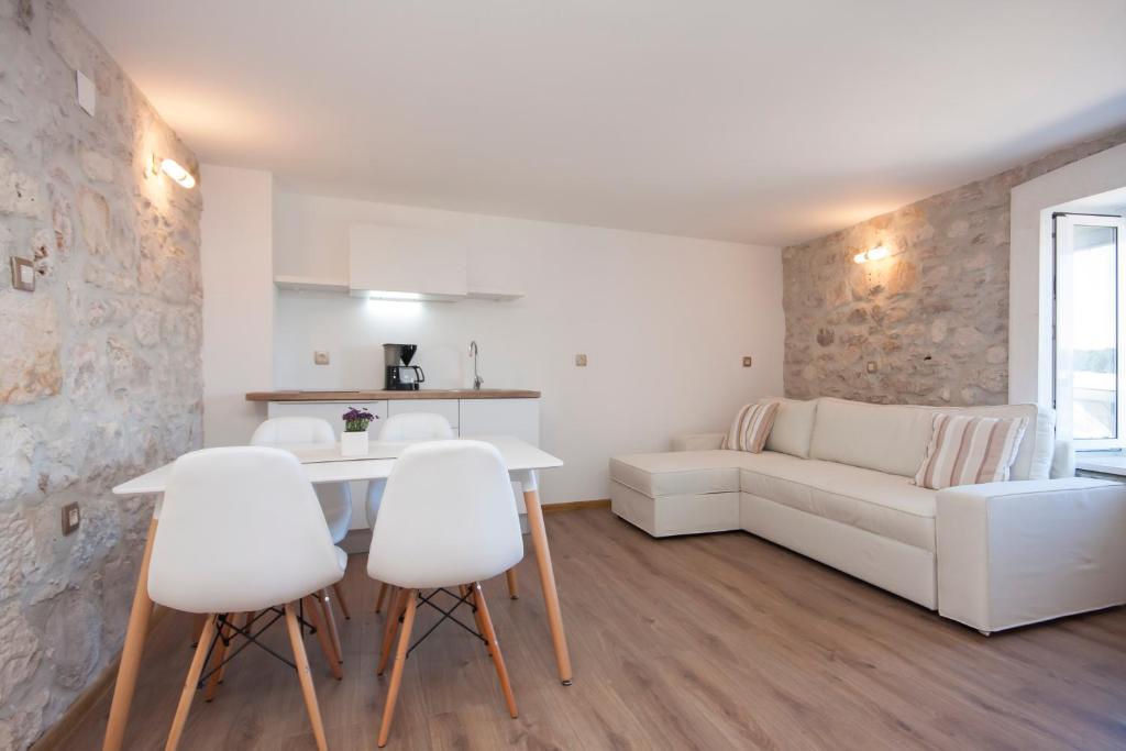 un soggiorno con divano bianco, tavolo e sedie di Apartments Dalmata a Krapanj (Crappano)