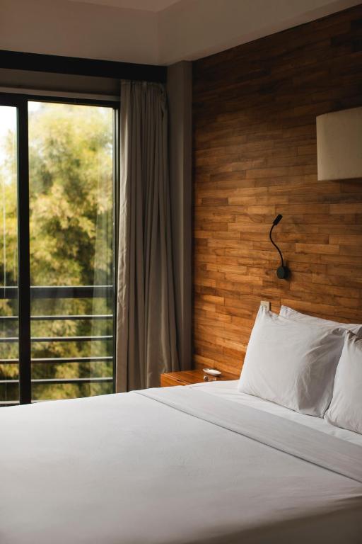 a bedroom with a bed and a large window at Surf Motel Canggu in Canggu