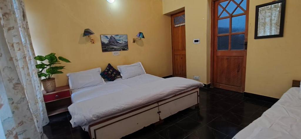 a bedroom with a bed with white sheets and a window at T-Suru Hotel & Cafe Leh in Leh