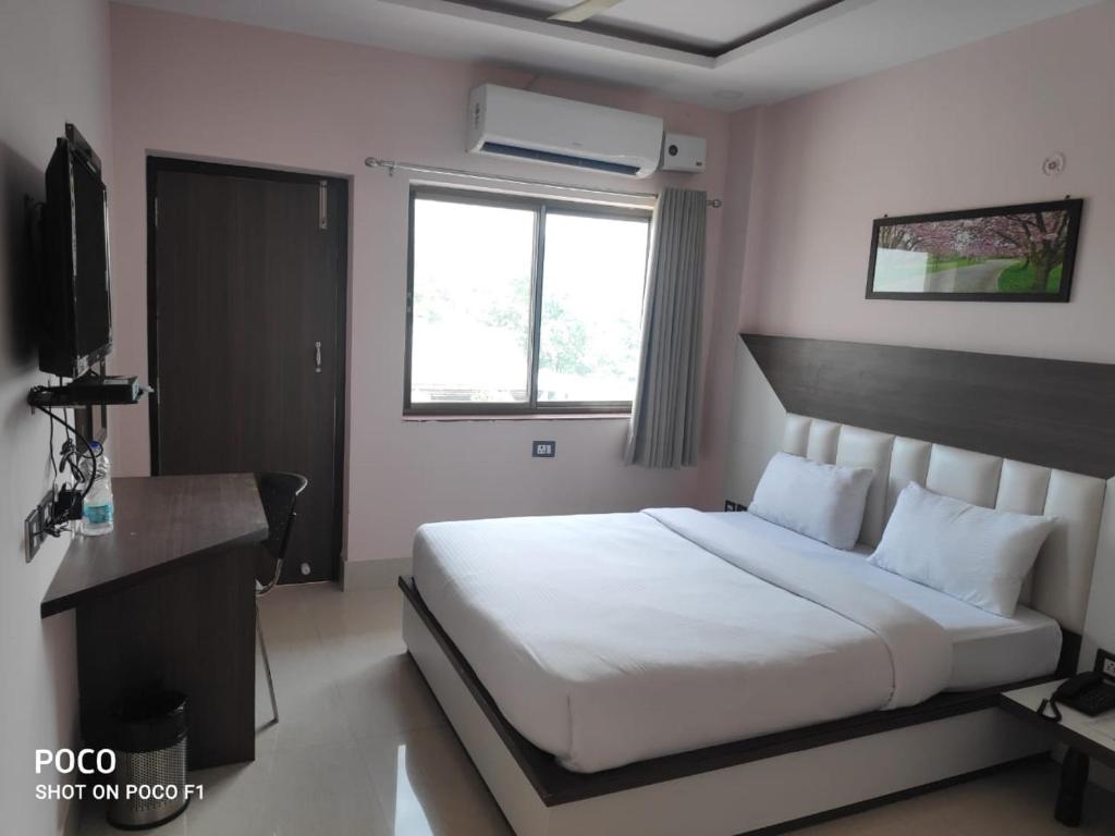 a bedroom with a white bed and a television at Hotel Centre Point in Gorakhpur