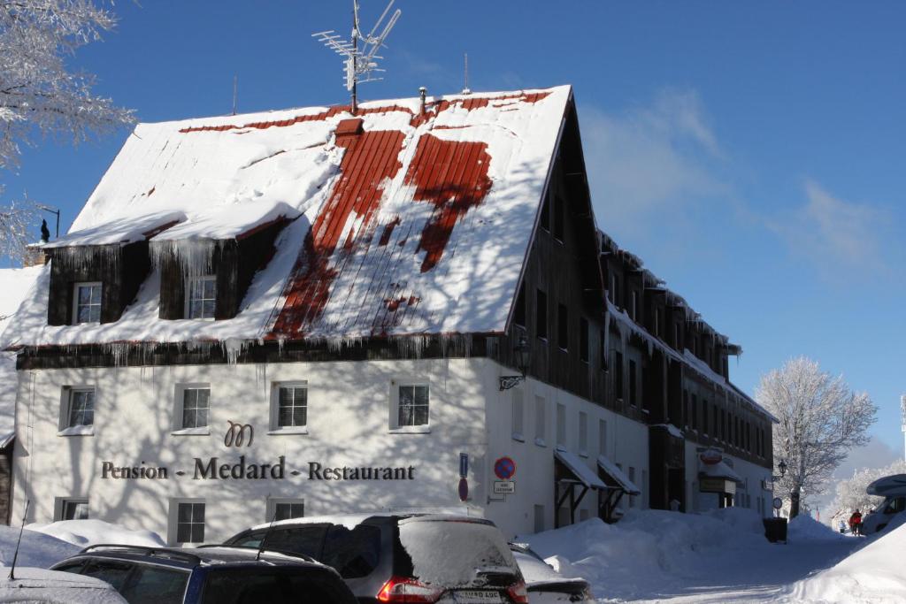 a building covered in snow with cars parked next to it at Pension Medard in Boží Dar