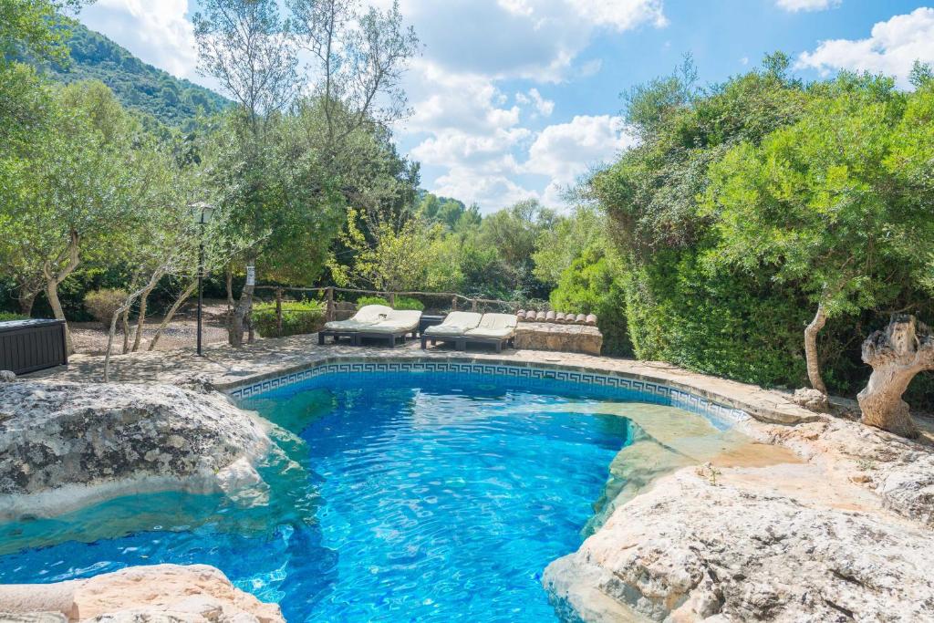a swimming pool in a yard with rocks and trees at Casa De Piedra in Campanet