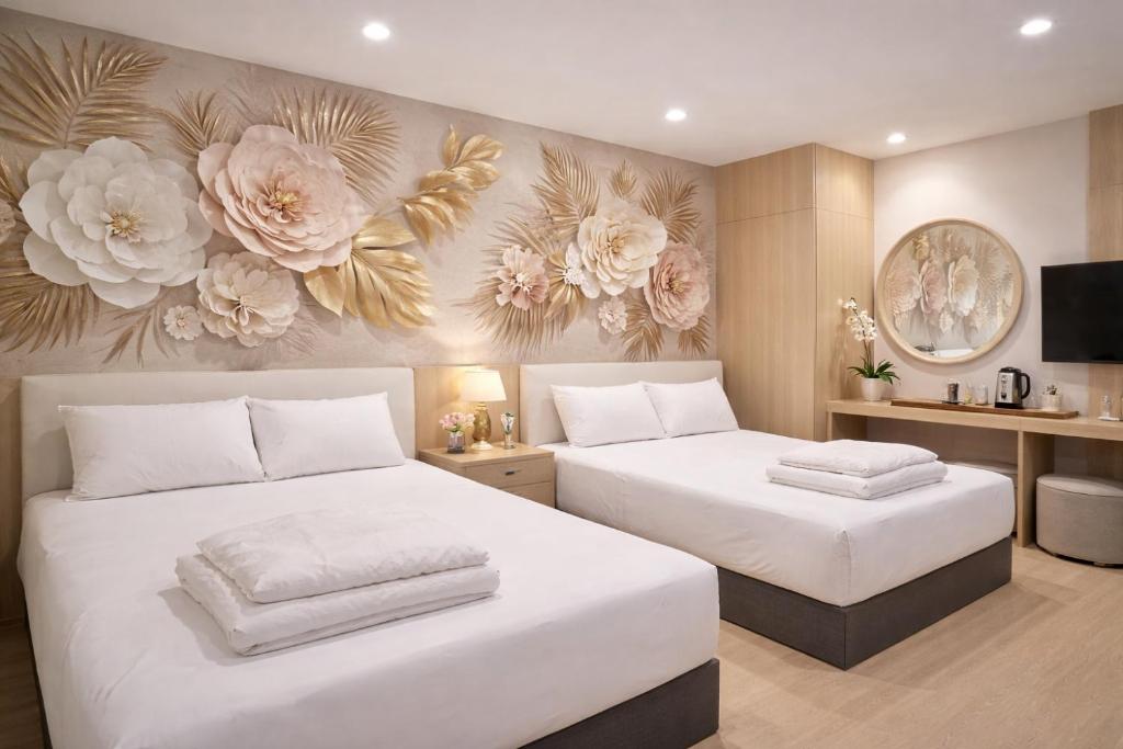 two beds in a bedroom with flowers on the wall at ARK Port Dickson Seafront Hotel in Port Dickson