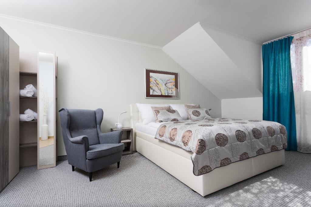 a white bedroom with a bed and a chair at Penzión Hradbová Residence & Spa in Košice