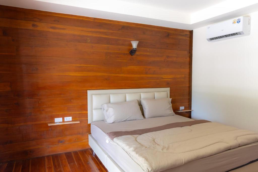 a bed in a room with a wooden wall at โอโซนริมน้ำเขาใหญ่ in Ban Pang Kae