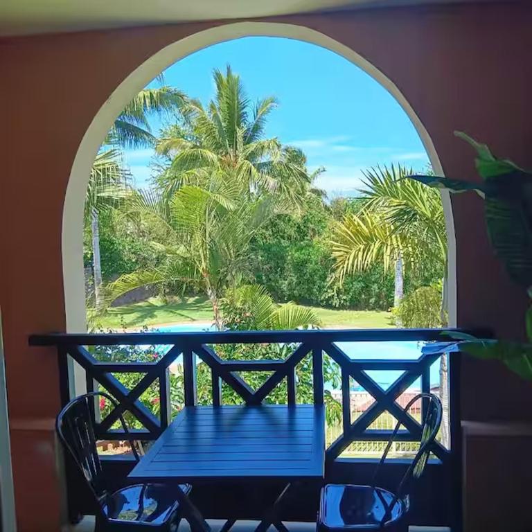 a blue table and chairs on a balcony with a window at Le Sable Blanc - piscine - parking - clim - wifi in Saint-Gilles-les-Bains