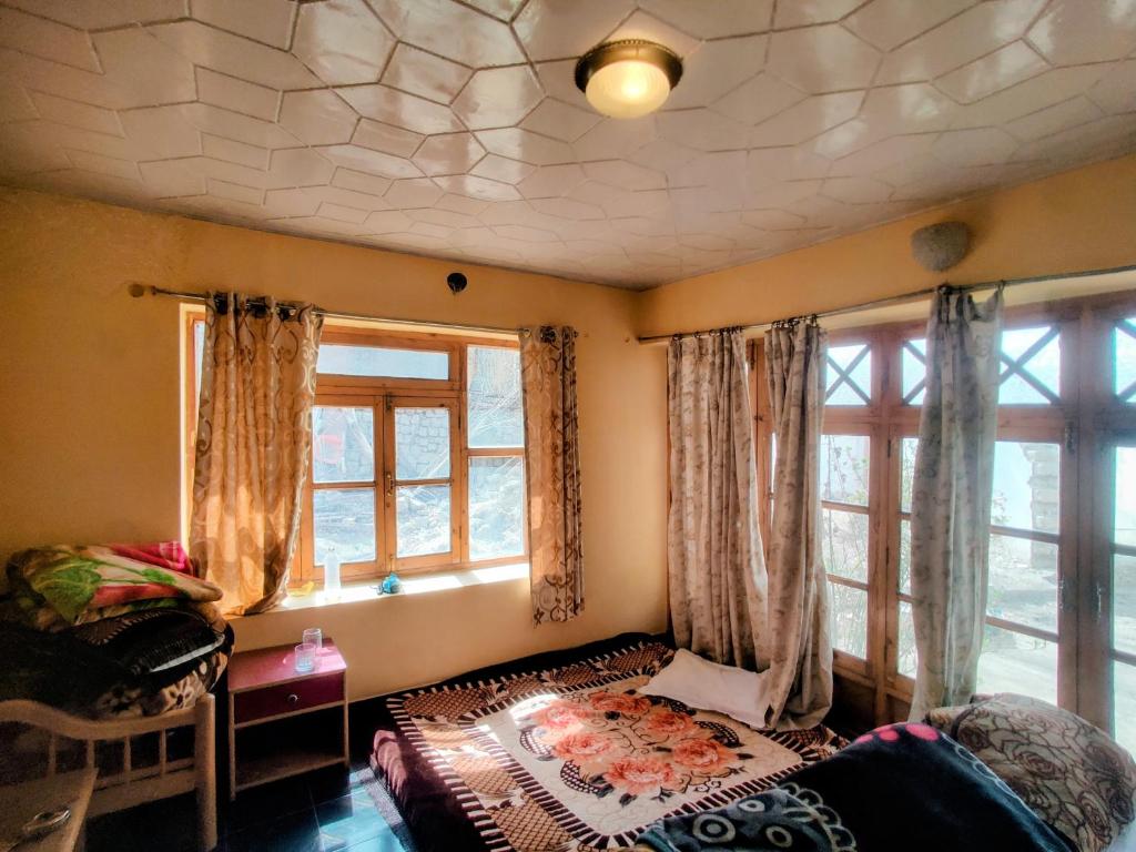 a bedroom with a bed and two windows at Hotel T-Suru Leh in Leh