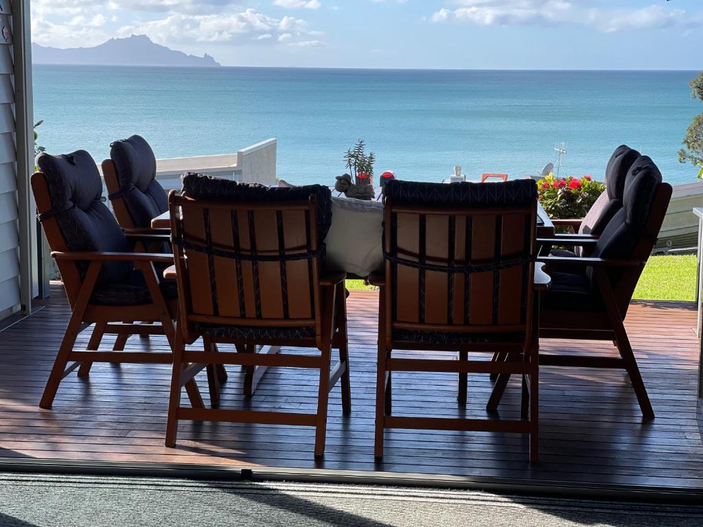 a table and chairs on a deck with the ocean at Lang's Beach Luxury Apartment in Langs Beach