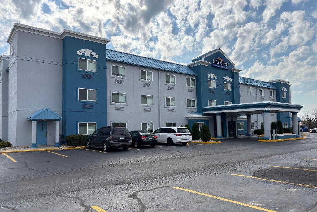 a large hotel with cars parked in a parking lot at Baymont by Wyndham Decatur IL North in Forsyth
