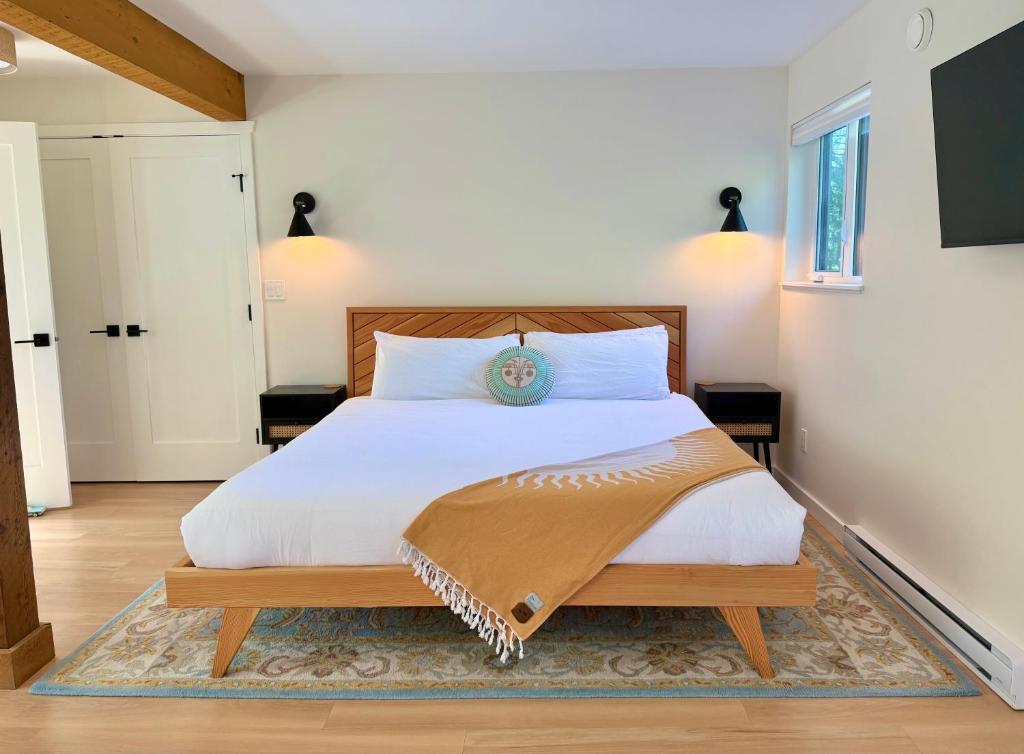 a bedroom with a white bed with a wooden headboard at Tofino Trailhead in Tofino