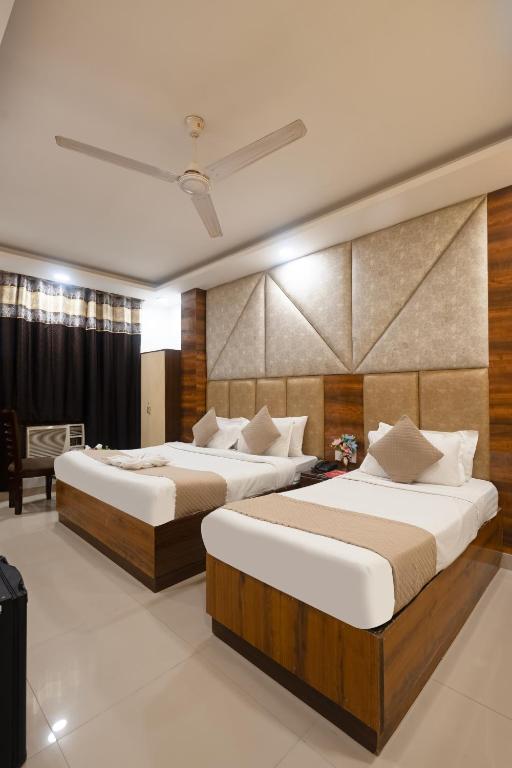 a hotel room with two beds and a chair at Hotel Daira Suite Near IGI Airport Delhi in New Delhi