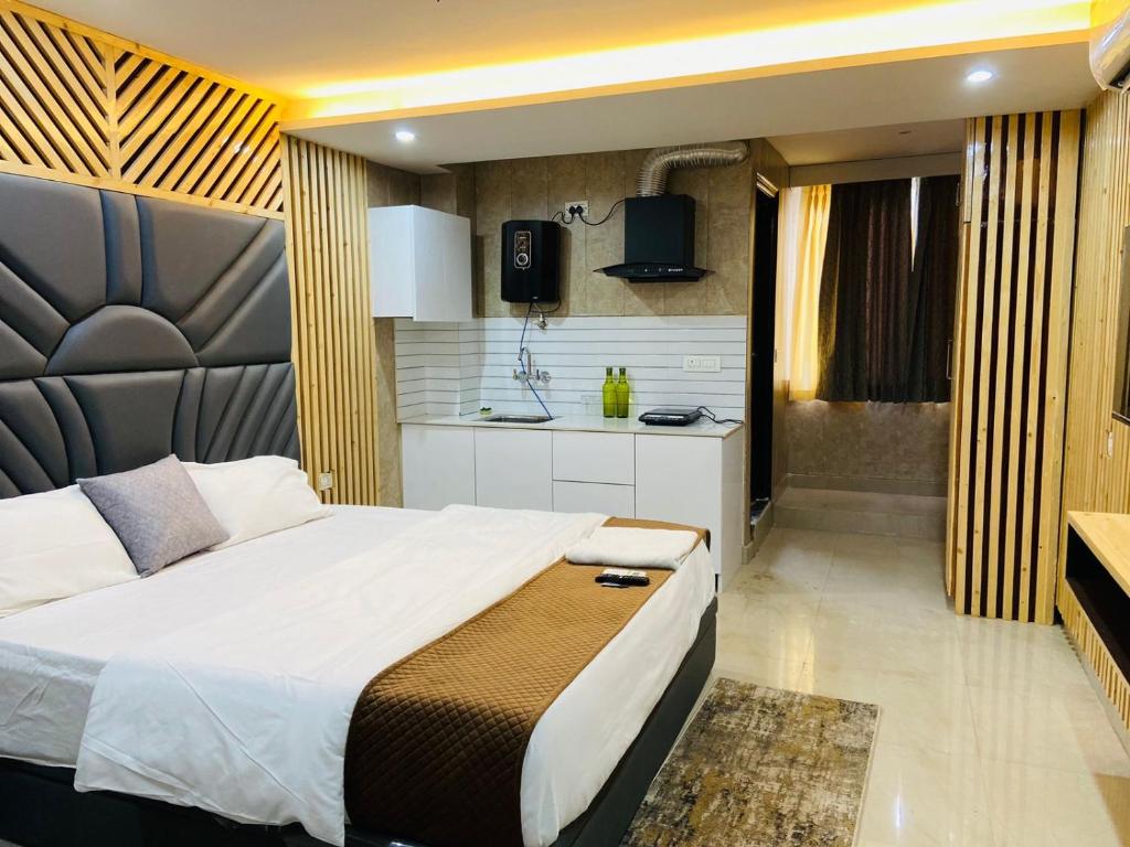 a bedroom with a large bed and a kitchen at The Warmwood Studio in Dehradun