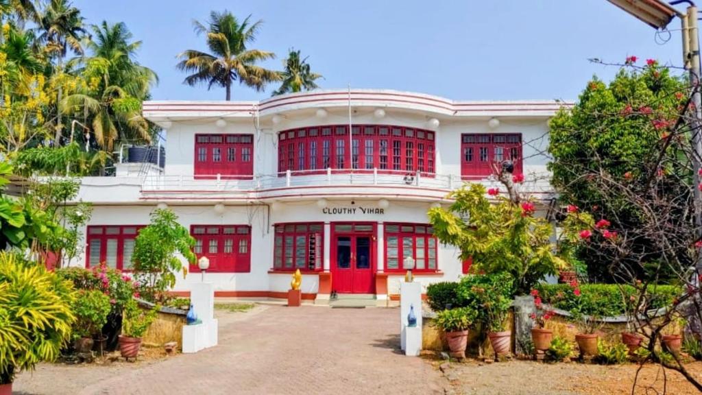 a large white building with red doors and trees at Clouthy Villa in Cochin