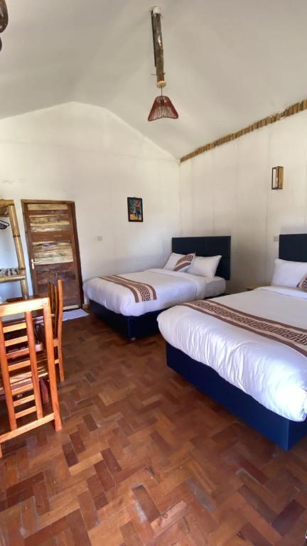 a bedroom with two beds and a wooden floor at AMBOKILI COTTAGES AMBOSELi in Nairobi
