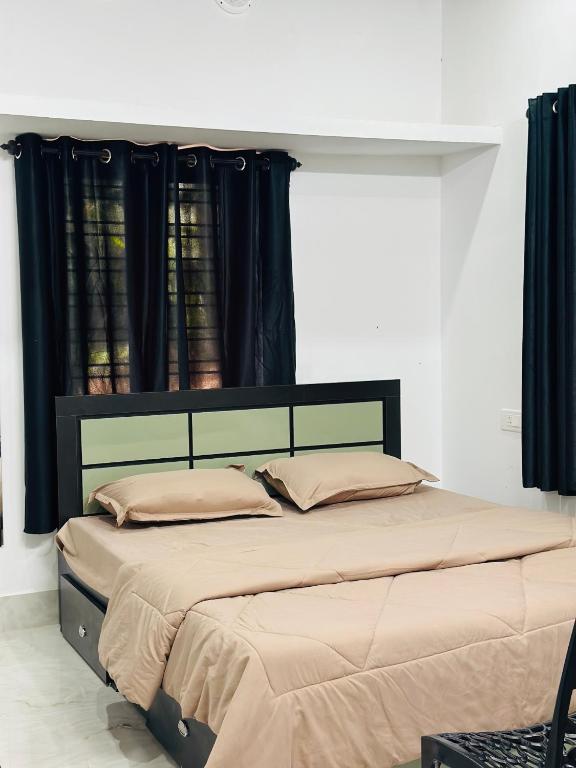 a bedroom with a large bed with black curtains at Mausam Homestay in Sultan Bathery