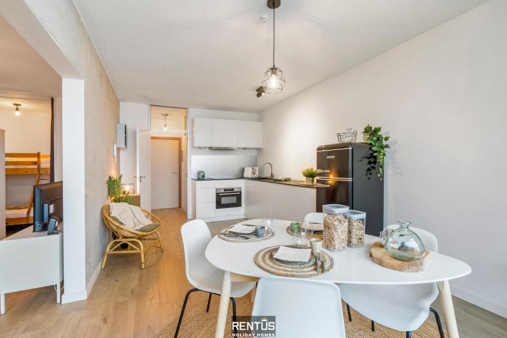 a kitchen and dining room with a white table and chairs at Sandy View - spacious studio flat near the beach in Nieuwpoort