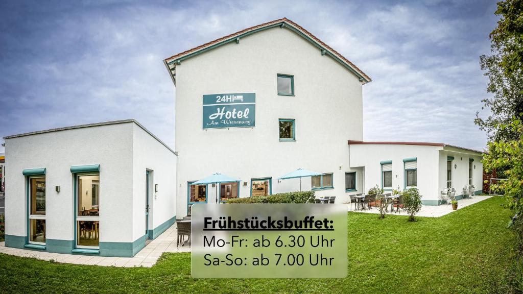 a white building with a sign in front of it at Hotel Am Wiesenweg l 24h check-in in Hausen