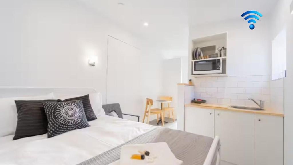 a white room with a bed and a kitchen at Nouvelle Studio in Epsom
