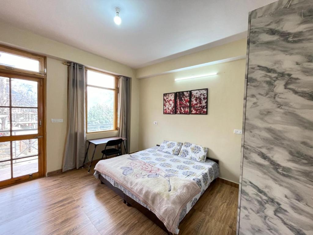 a bedroom with a bed and a desk in it at Aangan by Mom in Kalpa