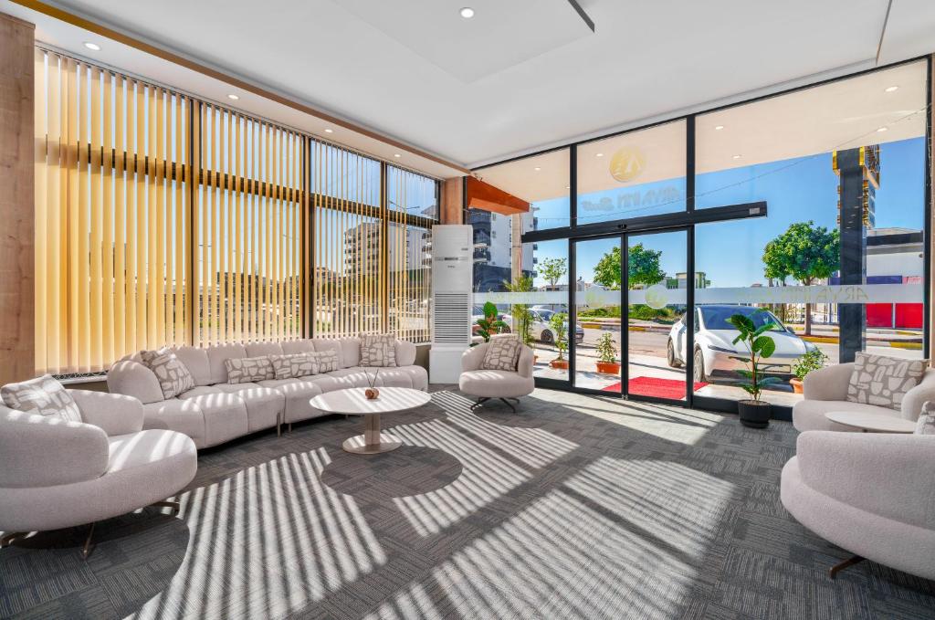 a living room with white furniture and large windows at Arya inn suit in Serik