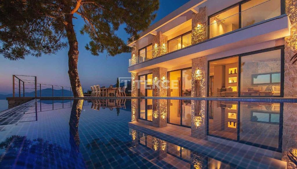 a large house with a swimming pool at night at TEKCE Villa Faralya N131 in Kızılcakaya