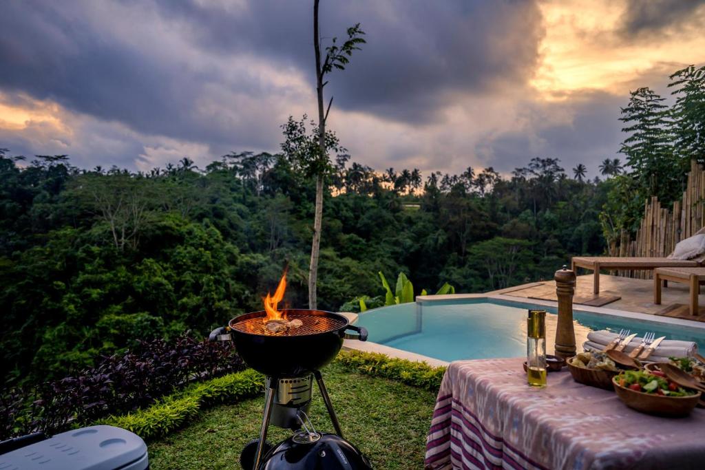 a bbq grill on a table next to a pool at Bubble 9 - Luxury Private Pool Experience Ubud in Tampaksiring