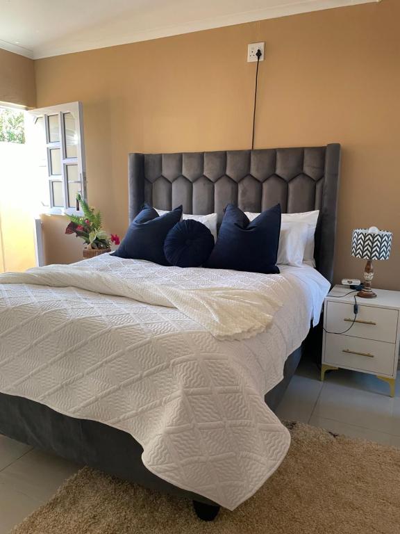 a bedroom with a large bed with blue pillows at Zambata Self Catering in Gqeberha