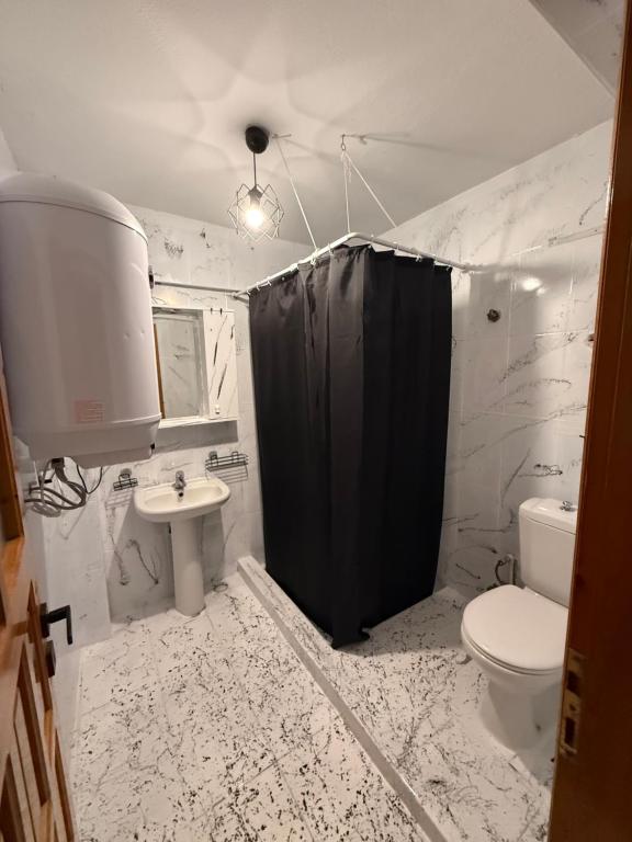 a bathroom with a black shower curtain and a toilet at Liva Konukevi in Ayvalık