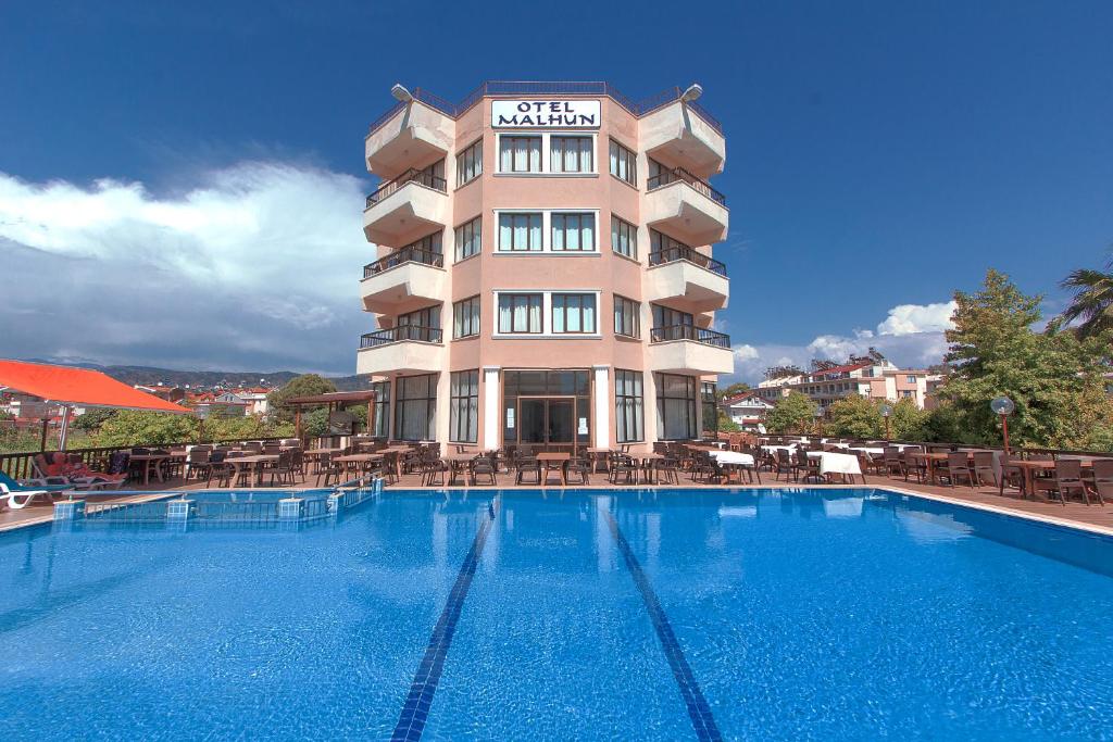 a hotel with a swimming pool in front of a building at Malhun Hotel in Fethiye