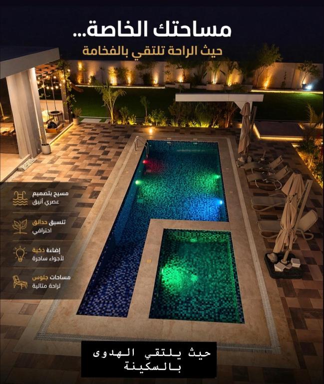 a swimming pool with green lights on a building at شاليه هوانا in Sohar