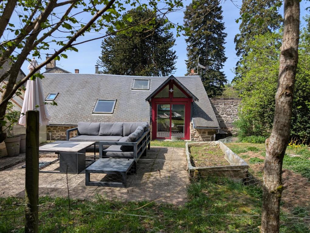 a backyard patio with a couch and a table at Gîte romantique avec charme et confort in Soubrebost