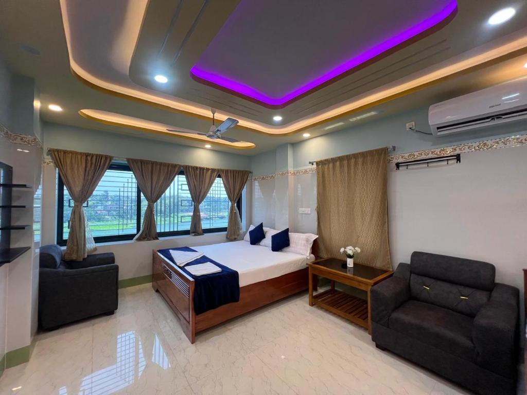 a bedroom with a bed and a couch and chairs at Hotel Raj in mayapur